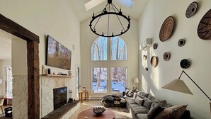 Uma sala de estar espaçosa com lareira, uma janela grande e um espaço de estar acolhedor.