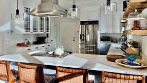Uma cozinha moderna com armários brancos, eletrodomésticos de aço inoxidável e uma ilha central com bancada.