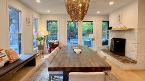 Un vaste espace dédié à la salle à manger, avec une grande table en bois, des bancs et une cheminée en pierre.