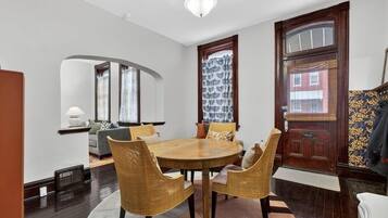 A dining area with a round wooden table, wicker chairs, and a chandelier.