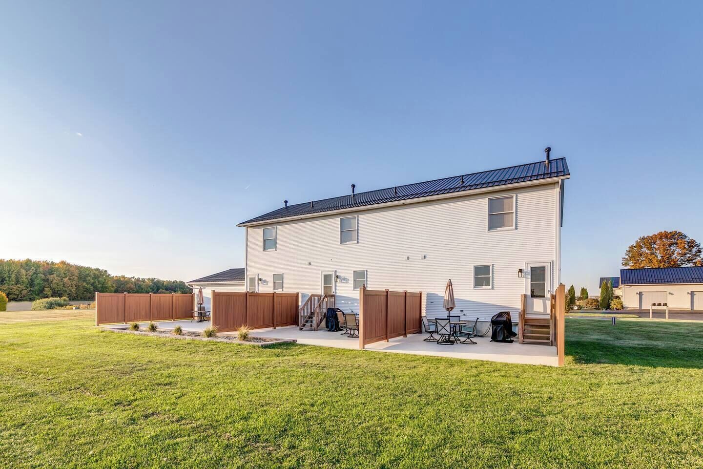 A two-story house with a fenced backyard, outdoor furniture, and a covered patio area.