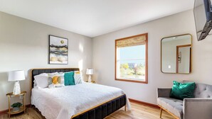 Een slaapkamer met een bed, nachtkastjes, een stoel, een raam en een spiegel.