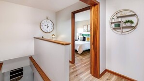Een gang met een houten plank, een wandklok en een rondom draaiend wandrek.