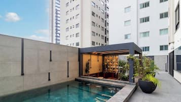 A rooftop pool area with a bar and seating, surrounded by high-rise buildings.