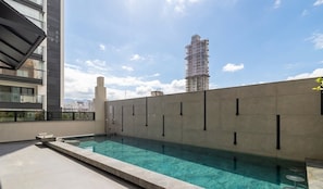 A rooftop pool with a clear view of the city skyline, a modern building with a glass facade, and a high-rise under construction. - Apt 300m From the Beach in Bldg w/ Pool Fnk1905 (Itapema)