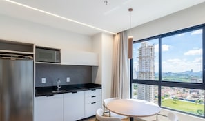 A modern kitchen with a built-in microwave, a stainless steel refrigerator, and a window with a city view. - Apt 300m From the Beach in Bldg w/ Pool Fnk1905 (Itapema)
