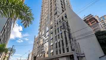 Un edificio alto con varios pisos, una señal que indica un espacio de negocios o oficinas, y líneas de electricidad.