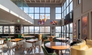 A spacious indoor area with multiple seating arrangements, large windows offering city views, and a modern chandelier. - Apt 300m From the Beach in Bldg w/ Pool Fnk1905 (Itapema)