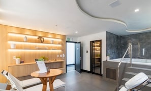 A modern hotel lobby with a reception desk, lounge chairs, a reception area with a wooden wall and shelves, and a spa area with a bathtub and shower. - Apt 300m From the Beach in Bldg w/ Pool Fnk1905 (Itapema)