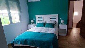A bedroom with a bed, two bedside tables, a window, and a door.