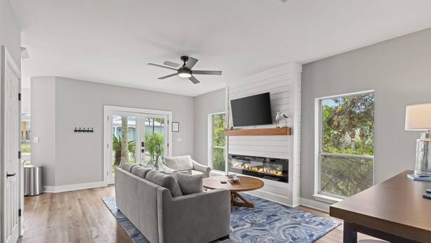 A modern living room with a gray sofa, a coffee table, a fireplace, and a TV mounted on the wall. - Blue Mountain Home, Pet friendly, Pool, 4 Bikes, Beach (Santa Rosa Beach)