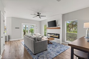 Ein modernes Wohnzimmer mit grauem Sofa, Couchtisch, Kamin und Wand-Fernseher.