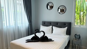 Une chambre à coucher moderne avec un grand lit, des rideaux gris, deux miroirs muraux et une table de chevet avec une lampe.