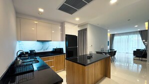Une cuisine moderne dotée d’un îlot central, de meubles en bois et d’un plan de travail noir.