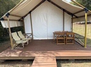 A tent with a wooden deck, two lounge chairs, and a table. - Glamping Tent w/ BBQ,  Pet-Friendly (Denison)