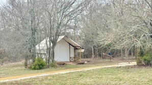 A small, single-story building with a simple, functional design, surrounded by trees and a grassy area.
