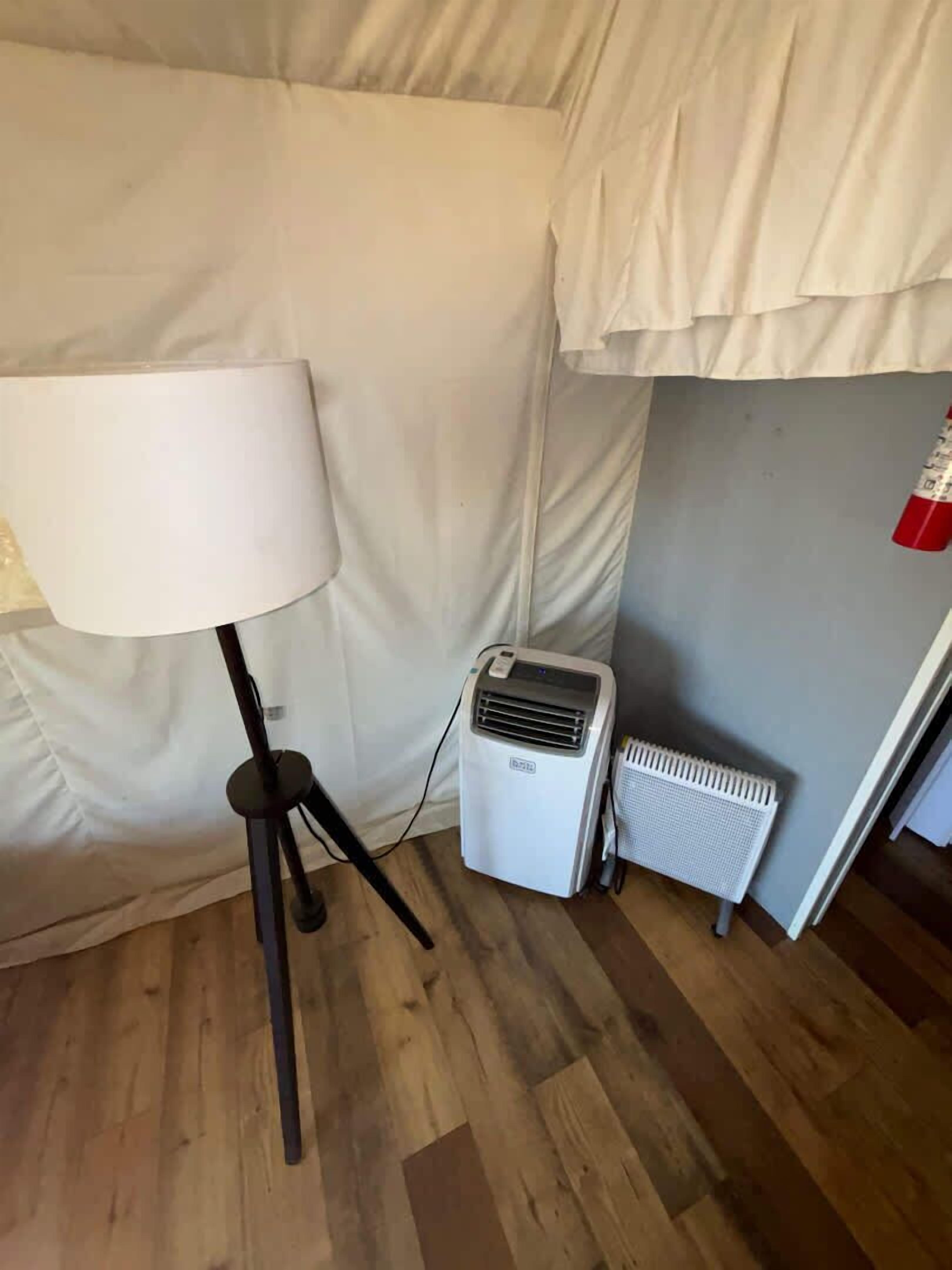 Ett hörnrum med en golvlampa, en luftkonditionering och ett element.