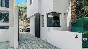 A modern building with a white exterior, a black door, and a small window. There is a paved area in front of the building, and a green dumpster labeled with the number 2. - Northside Retreat - Infinity pool - Fast Wi-Fi (Sayulita)
