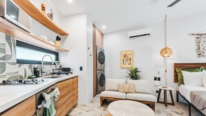 A compact living space with a kitchenette, a sofa, a round coffee table, and a bed. - Northside Retreat - Infinity pool - Fast Wi-Fi (Sayulita)