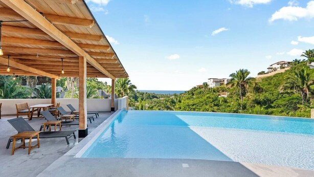 A pool area with lounge chairs and a wooden pergola, overlooking a lush landscape and the ocean. - Northside Retreat - Infinity pool - Fast Wi-Fi (Sayulita)