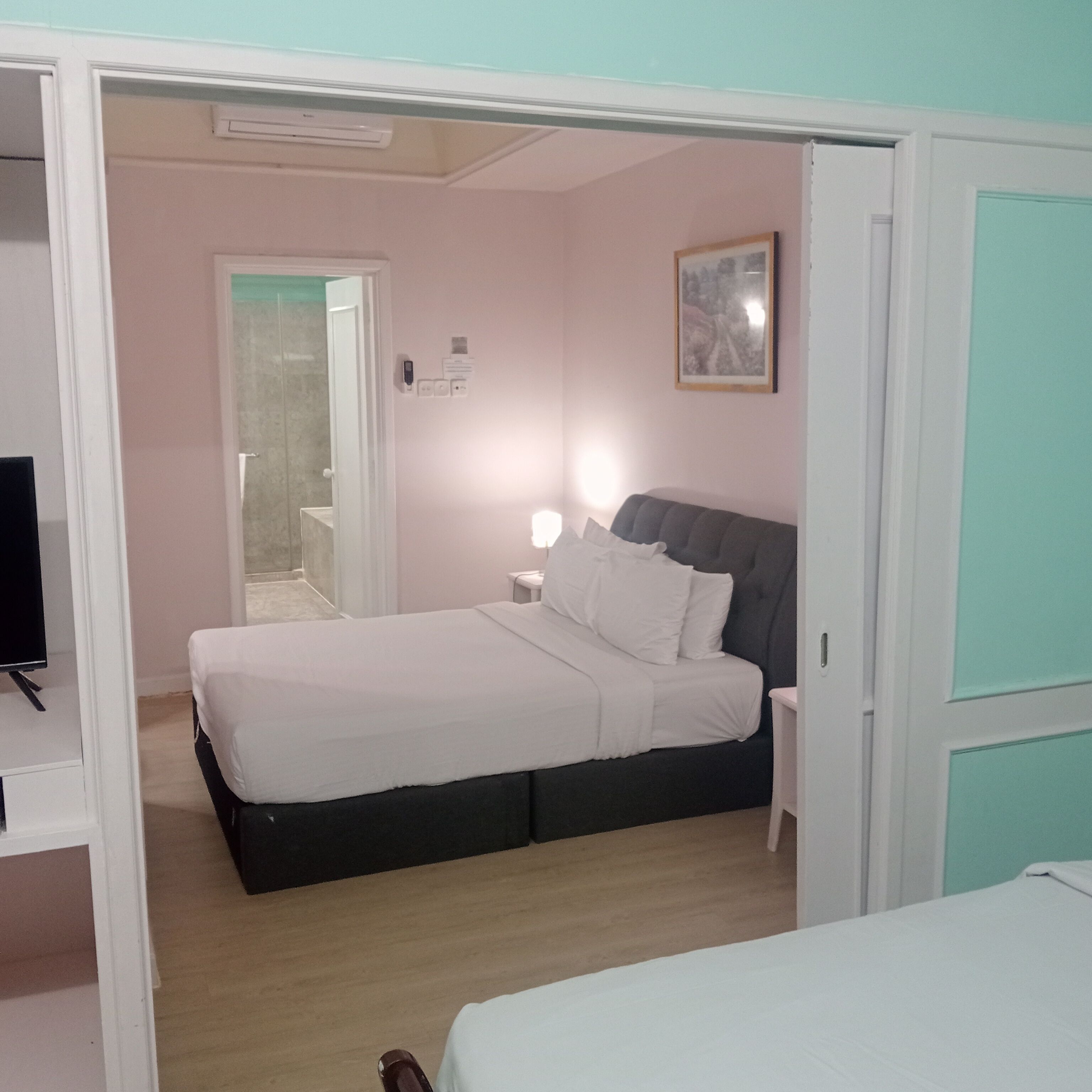 Un dormitorio con cama, mesita de noche y televisor.