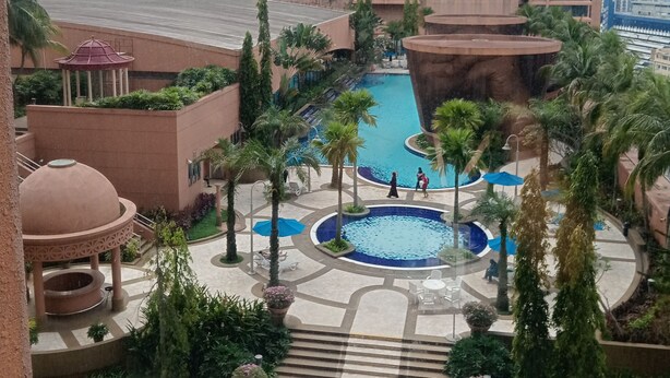 Un resort con piscina central, palmeras y un pabellón.