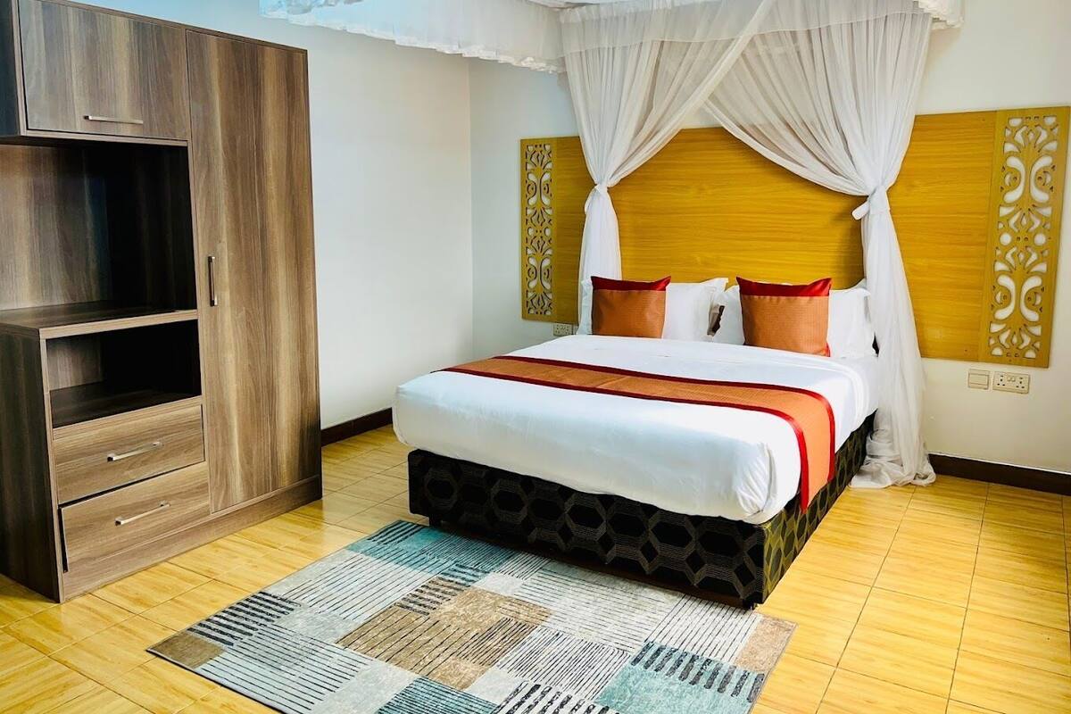 A hotel room with a bed, a wardrobe, and a decorative headboard.