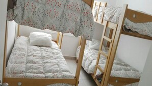 Une chambre avec trois lits superposés, chacun doté d’une structure en bois et de draps à motifs floraux.