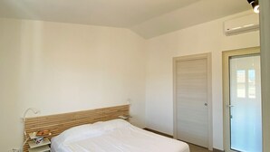 A bedroom with a single bed, a wooden headboard, a bedside table, and a closed door. - La Casetta (Stalettì)