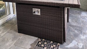 Ein Sitzbereich im Freien aus Rattangeflecht mit einem Tisch und zwei Holztassen.