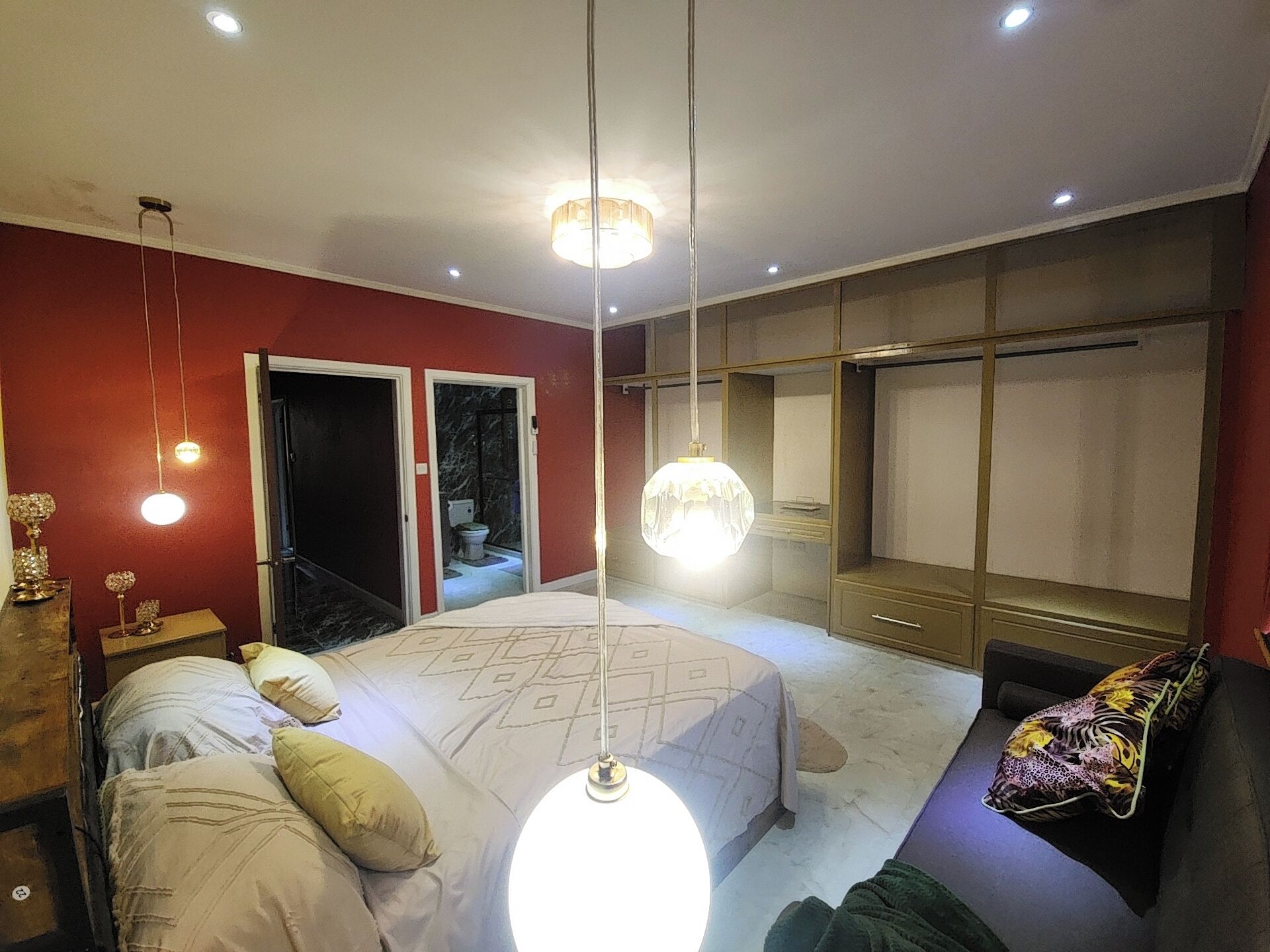Un dormitorio con cama, armario y baño visible a través de una puerta abierta.