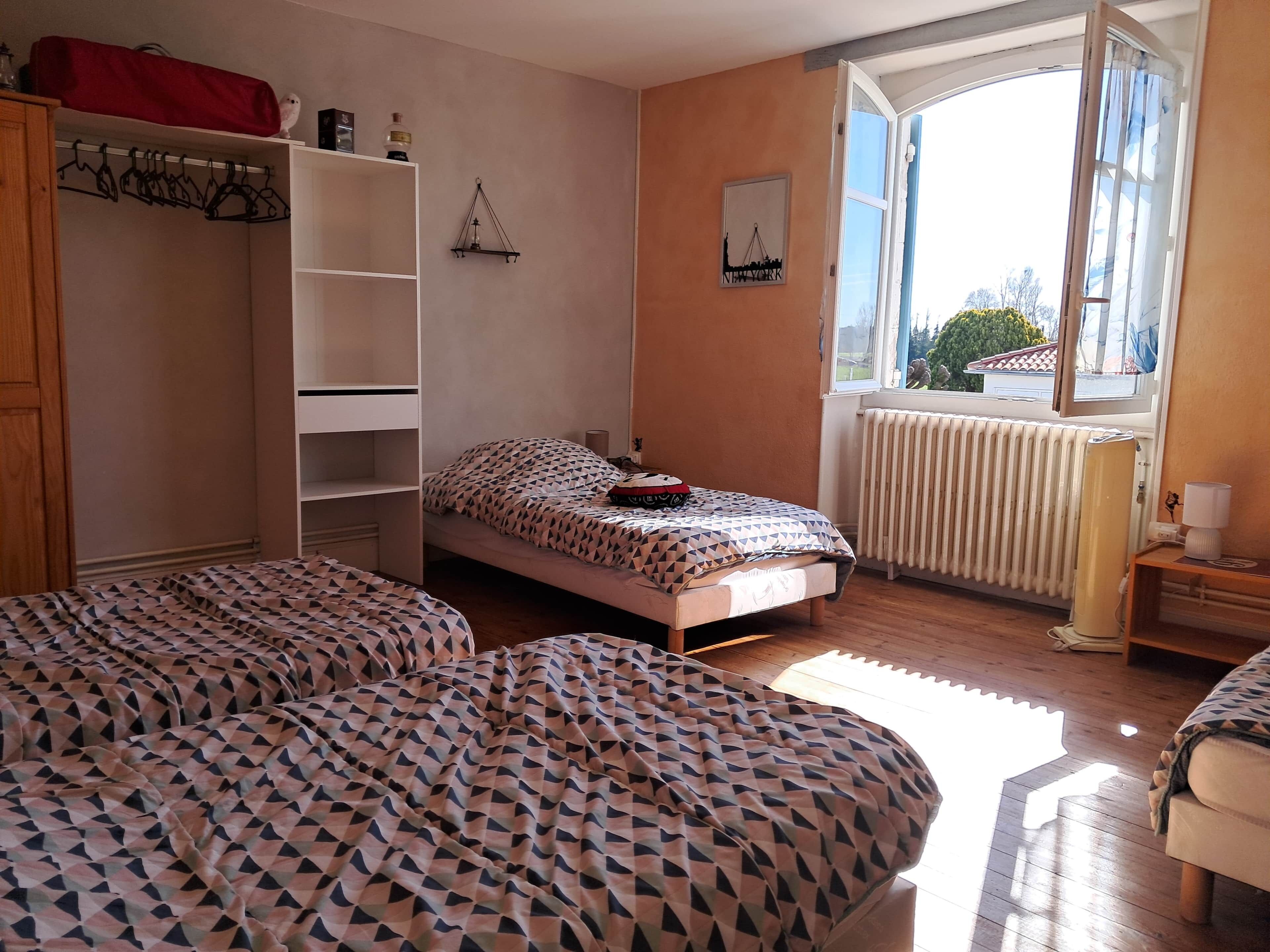 Une chambre à coucher avec un lit, une armoire, un radiateur et une fenêtre donnant sur un beau paysage.