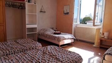 Une chambre à coucher avec un lit, une armoire, un radiateur et une fenêtre donnant sur un beau paysage.