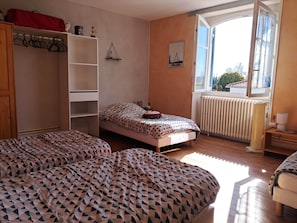 Une chambre à coucher avec un lit, une armoire, un radiateur et une fenêtre donnant sur un beau paysage.
