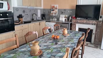 Una cocina moderna con armarios de madera, una mesa de comedor con mantel estampado y un televisor.