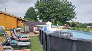 An outdoor swimming pool area with inflatable toys, lounge chairs, and a wooden deck.