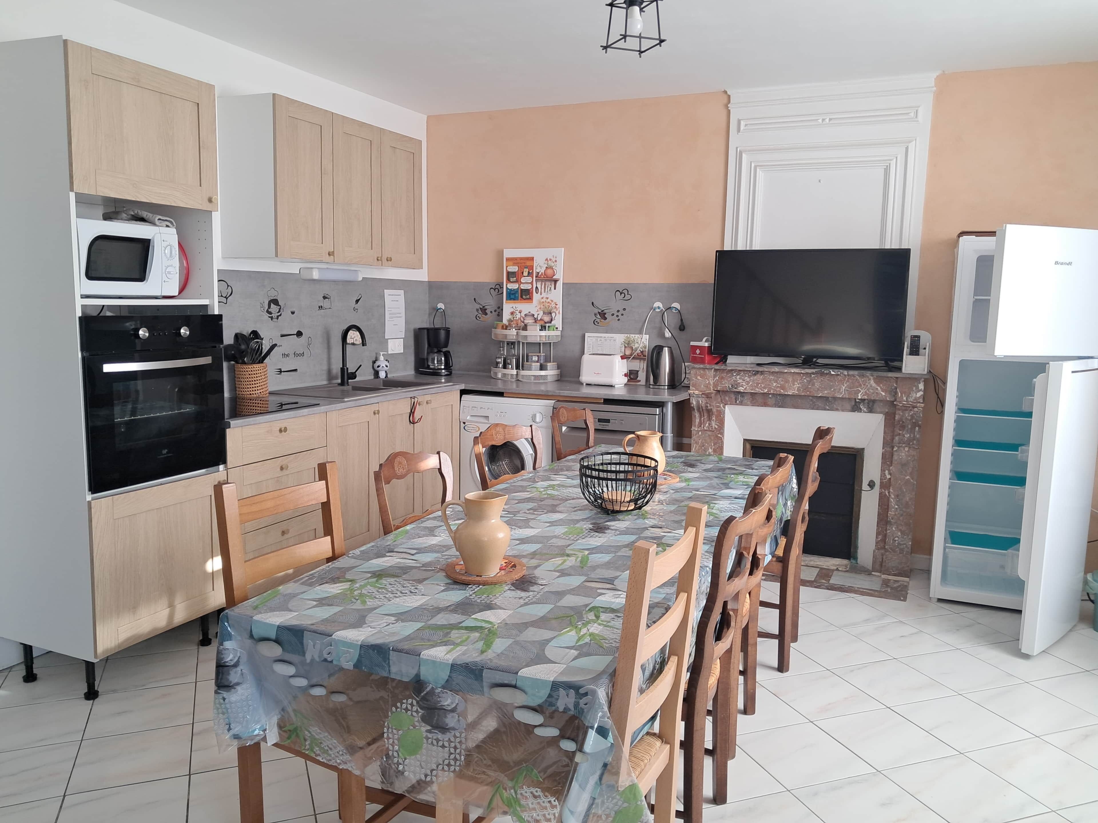 A kitchen with wooden cabinets, a microwave, oven, and a dining table with chairs.