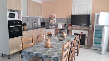 A kitchen with wooden cabinets, a microwave, oven, and a dining table with chairs.