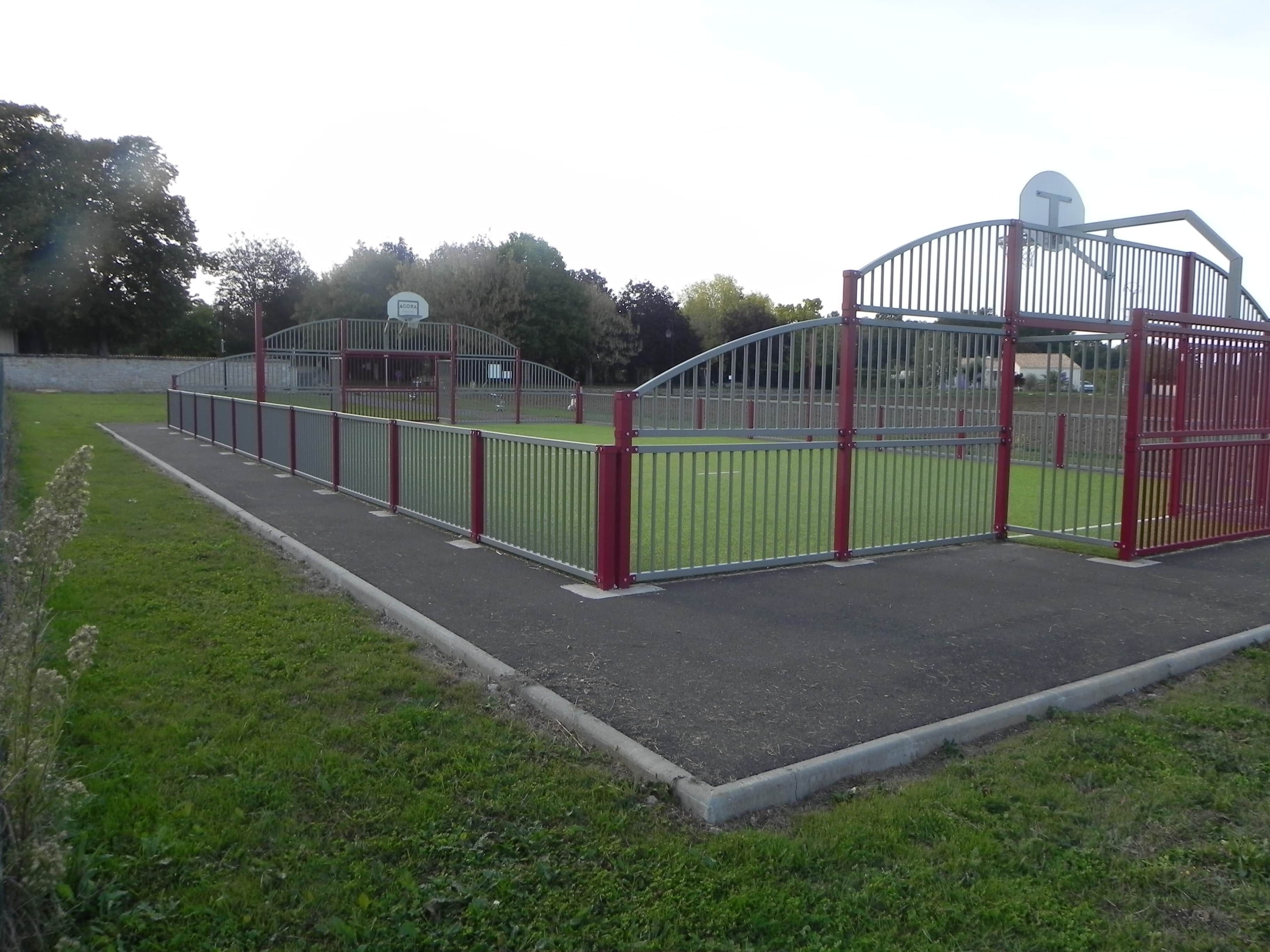 A fenced sports facility with a basketball court, a tennis court, and a covered seating area.