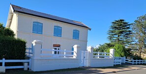 A two-story building with a white facade, a gated entrance, and a clear blue sky.