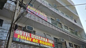 Un edificio a più piani con un cartello che indica Hotel Dwarka Inn, con camere dotate di aria condizionata e numero di reception.