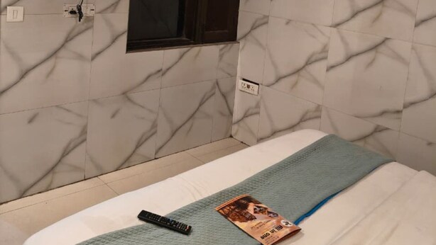 Una camera d'albergo con un letto, una TV a muro, una finestra e un condizionatore d'aria.