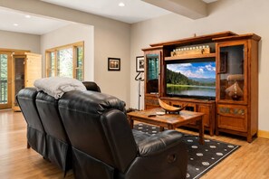 A living room with a leather sofa, a television, and a wooden cabinet. - Hot Tub· Game Room· Sauna· Mtn Views· Dog Friendly (Breckenridge)