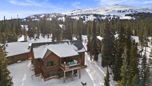 A lodge with a snow-covered deck and a hot tub, surrounded by a forest and a snow-capped mountain in the background. - The Summit at 11 • 15 Min to Breck • Private Hot Tub Views •  Sauna •... (Breckenridge)