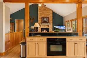 A kitchen with a brick fireplace, wooden cabinets, and a view of a lake through large windows. - Hot Tub· Game Room· Sauna· Mtn Views· Dog Friendly (Breckenridge)