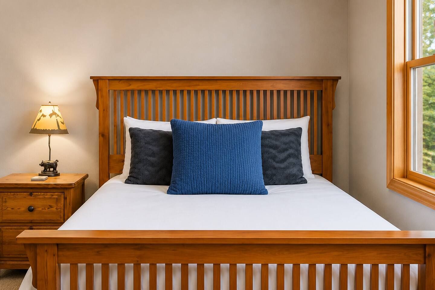 Un dormitorio con cabecera de madera, una mesita de noche con lámpara y una ventana con vistas.