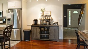 Una cocina moderna con un refrigerador de acero inoxidable, armarios de madera y una barra para café.