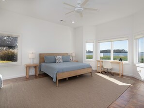 A bedroom with a bed, bedside tables, a desk, and a view of a lake. - Sunset Shores | an ESVR property (Royal Oak)