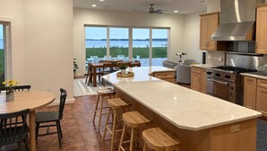 A modern kitchen with a large island, stainless steel appliances, and a view of the outdoors. - Sunset Shores | an ESVR property (Royal Oak)