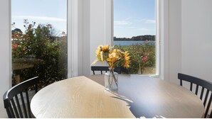 A dining table with a vase of yellow flowers, two chairs, and a view of a lake through a window. - Sunset Shores | an ESVR property (Royal Oak)